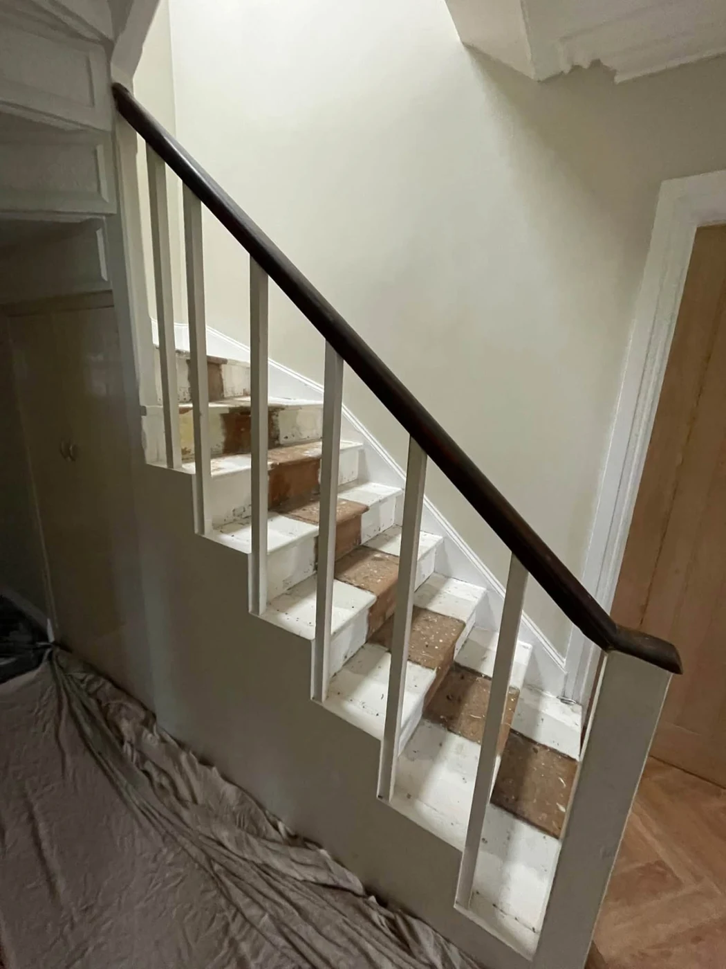 Before: original staircase with straight spindles and plain under-stairs wall