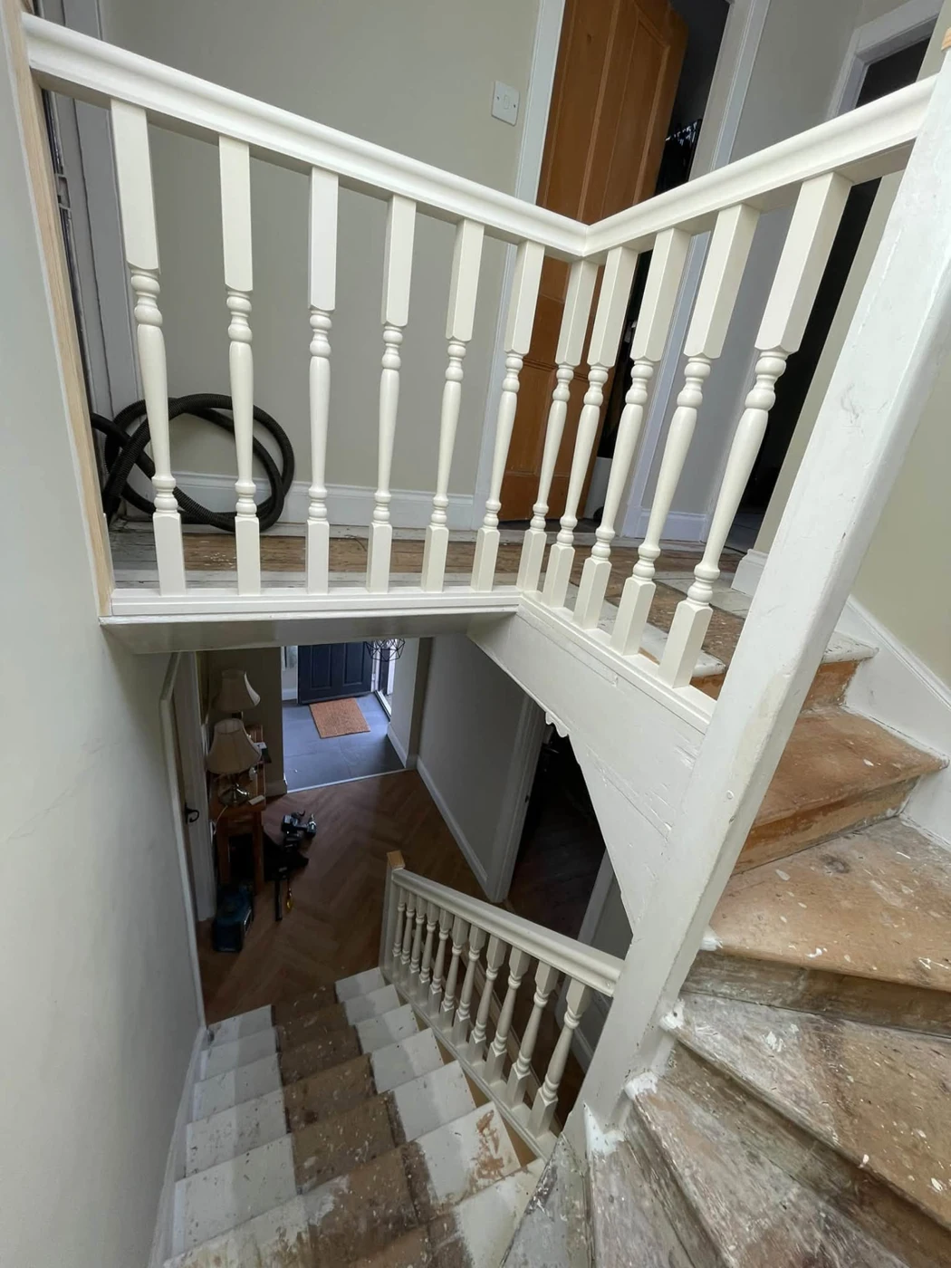 New painted landing balustrade with turned spindles; stair finishes in progress